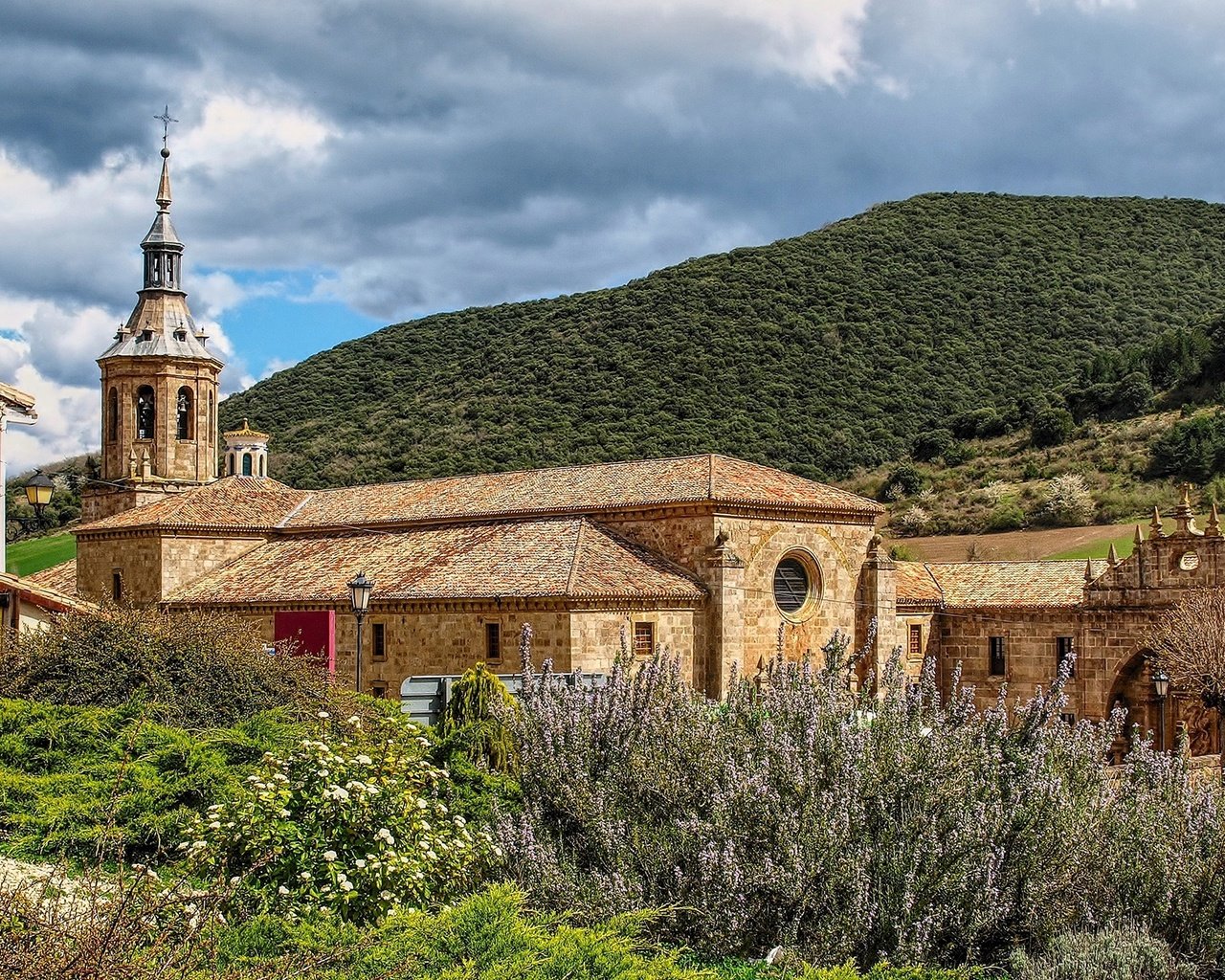 Обои небо, монастырь, трава, la rioja, monasterio de yuso, облака, горы, солнце, лес, кусты, испания, the sky, the monastery, grass, clouds, mountains, the sun, forest, the bushes, spain разрешение 1920x1253 Загрузить