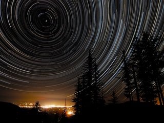 Обои ночь, деревья, звезды, город, star trails, night, trees, stars, the city разрешение 1920x1200 Загрузить