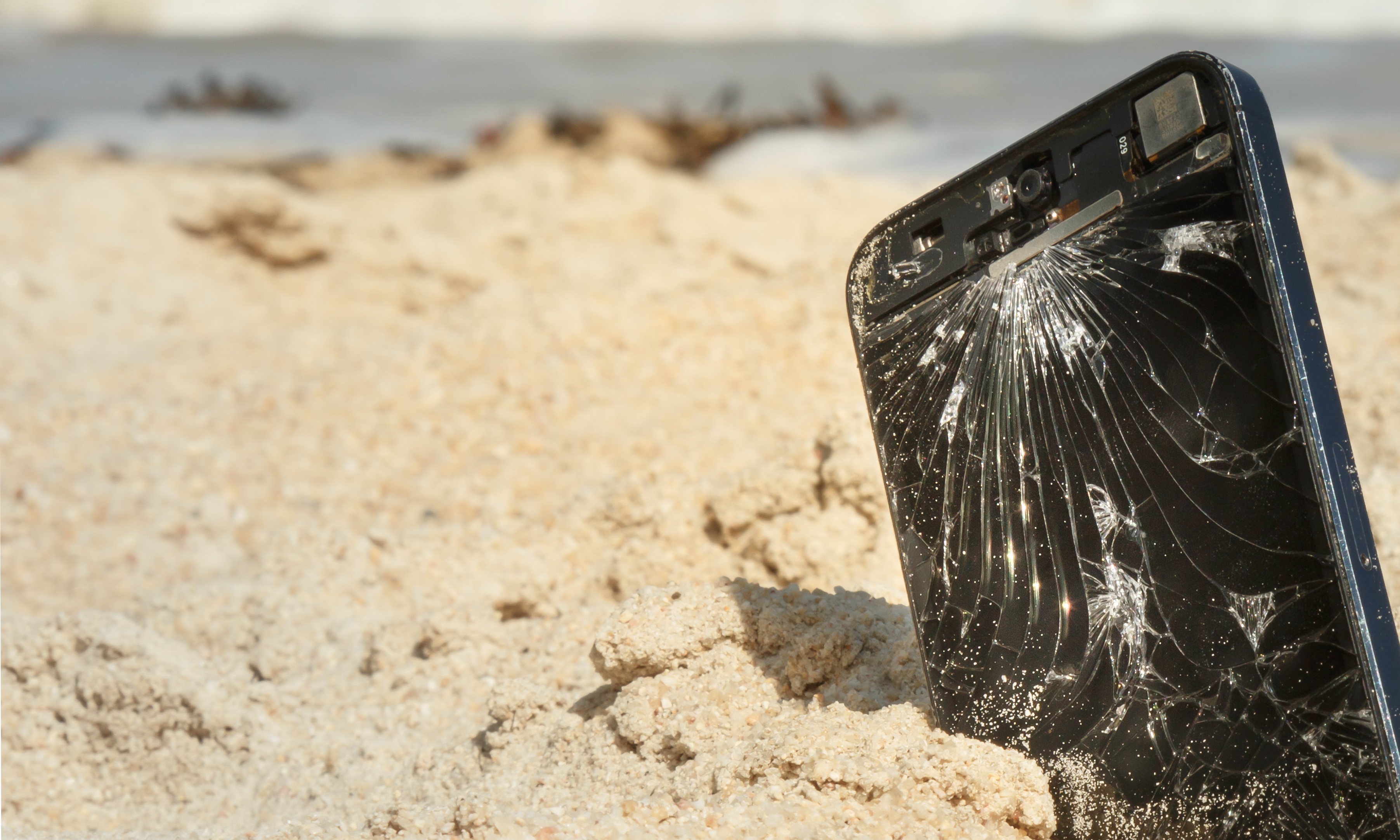 Фото разбивать телефон. Разбитый смартфон. Смартфон в песке. Разбитый айфон. Сломанный смартфон.